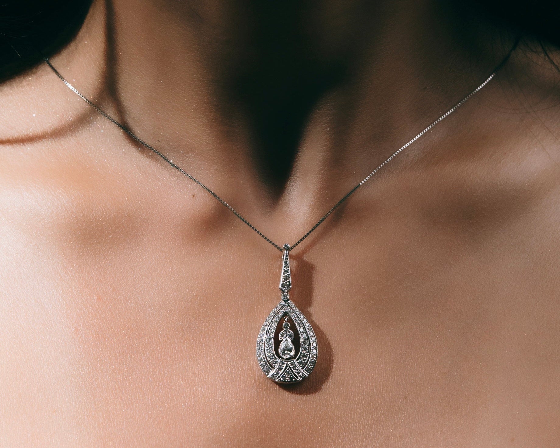 Person wearing a long pendant diamond necklace.