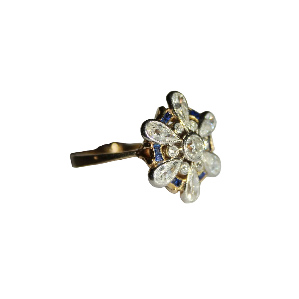 Gold ring with floral design and gemstones on a white background