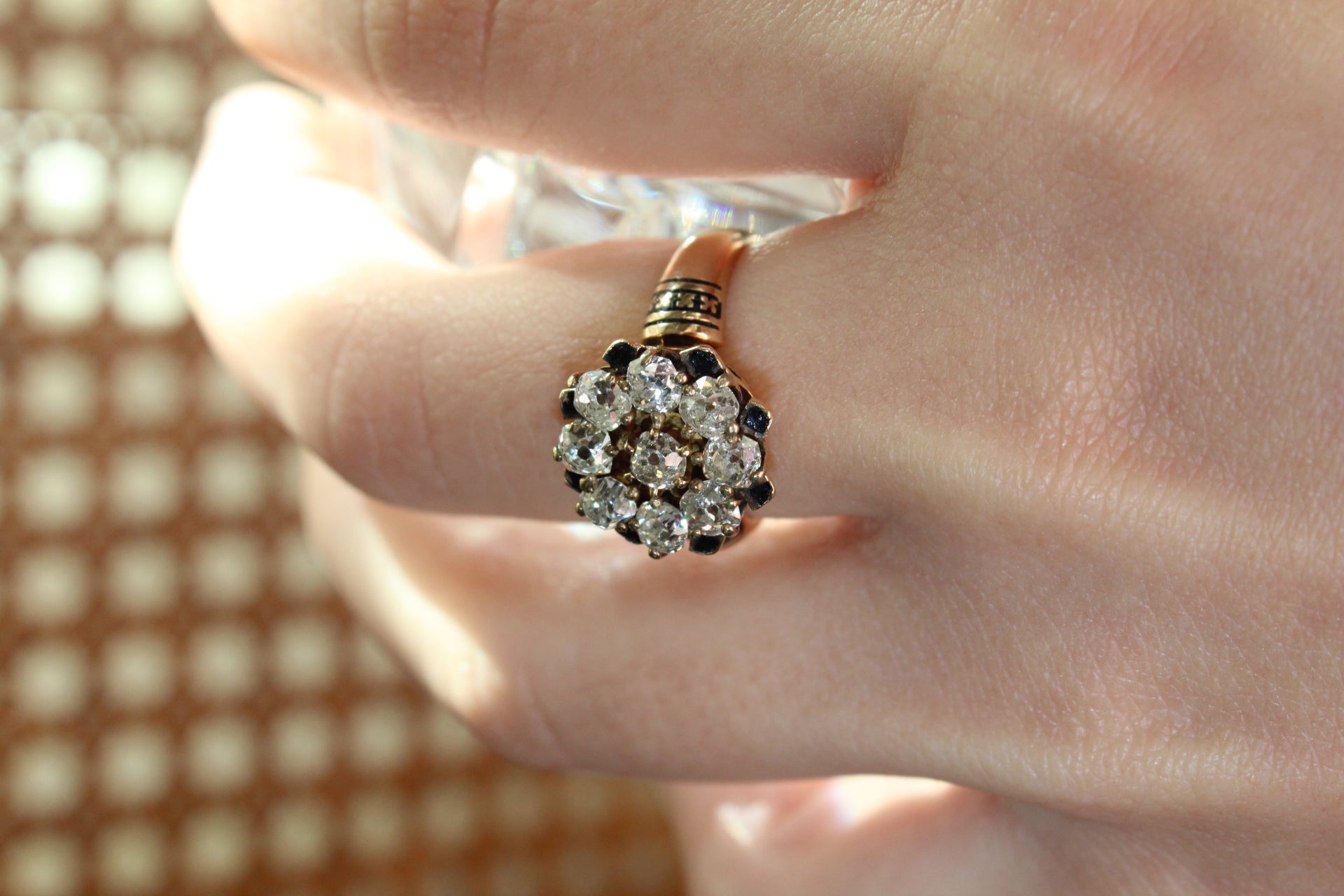 Close-up of a hand wearing a decorative ring with a patterned background
