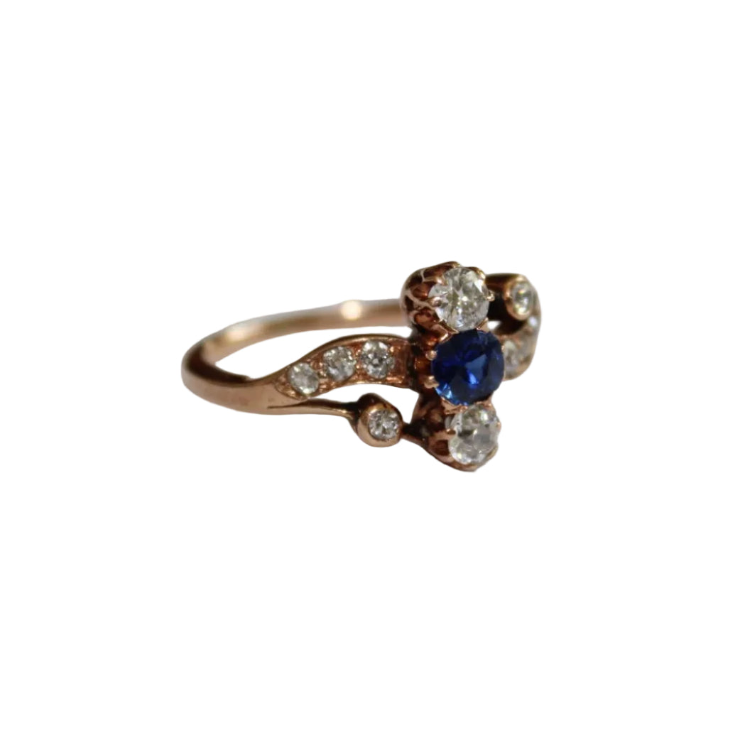 Rose gold ring with a blue gemstone and diamonds on a white background