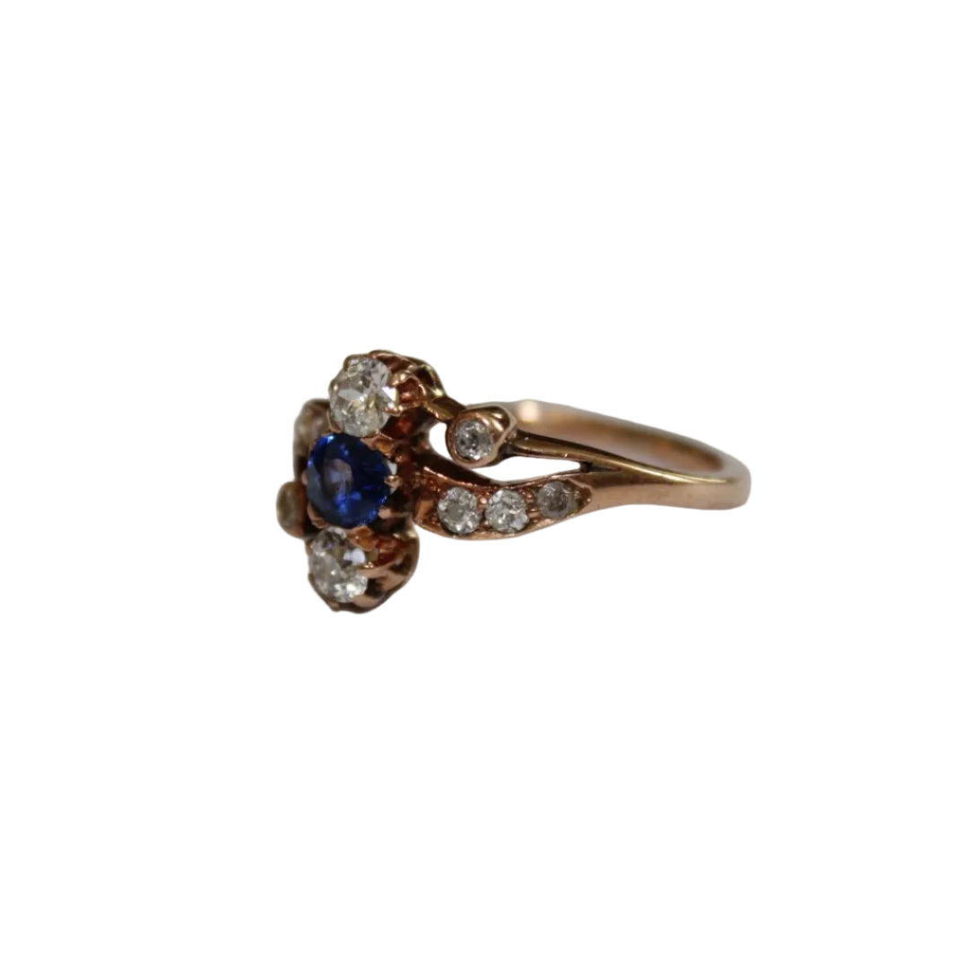Rose gold ring with a blue gemstone and diamonds on a white background