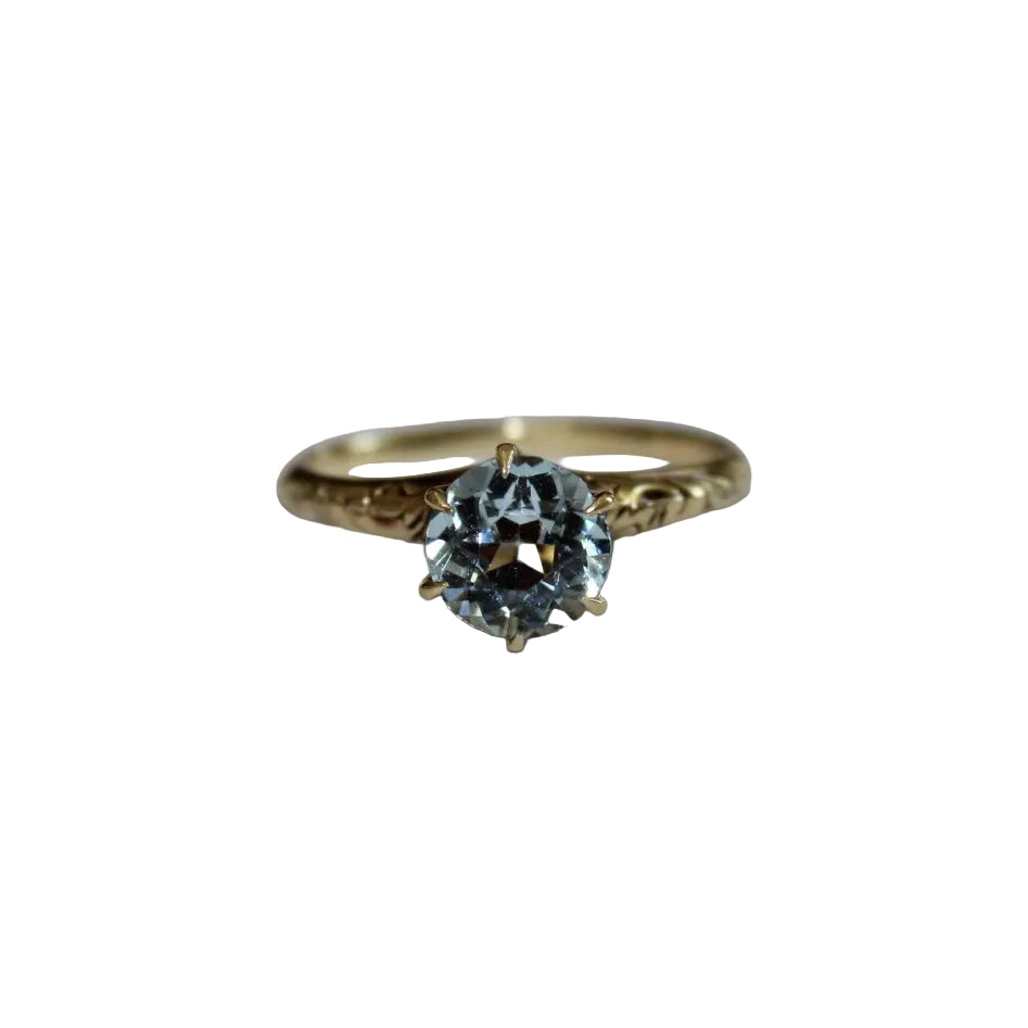 Gold ring with a blue gemstone on a white background