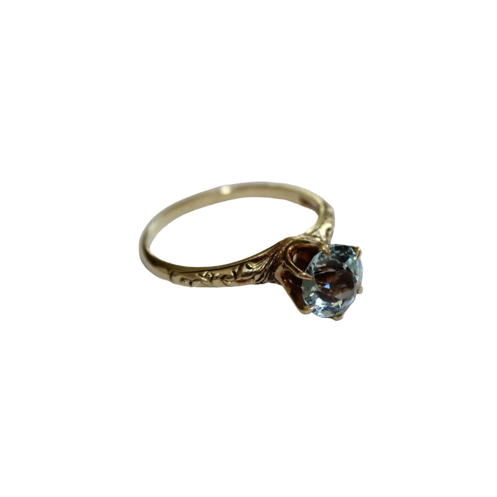 Gold ring with a blue gemstone on a white background