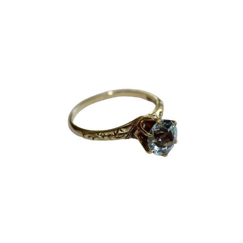 Gold ring with a blue gemstone on a white background