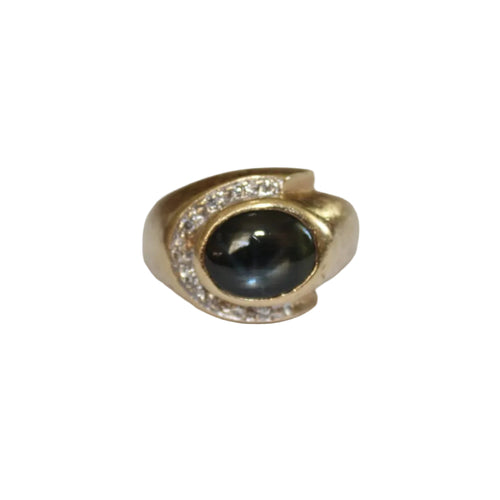 Gold ring with a black gemstone and clear stones on a white background