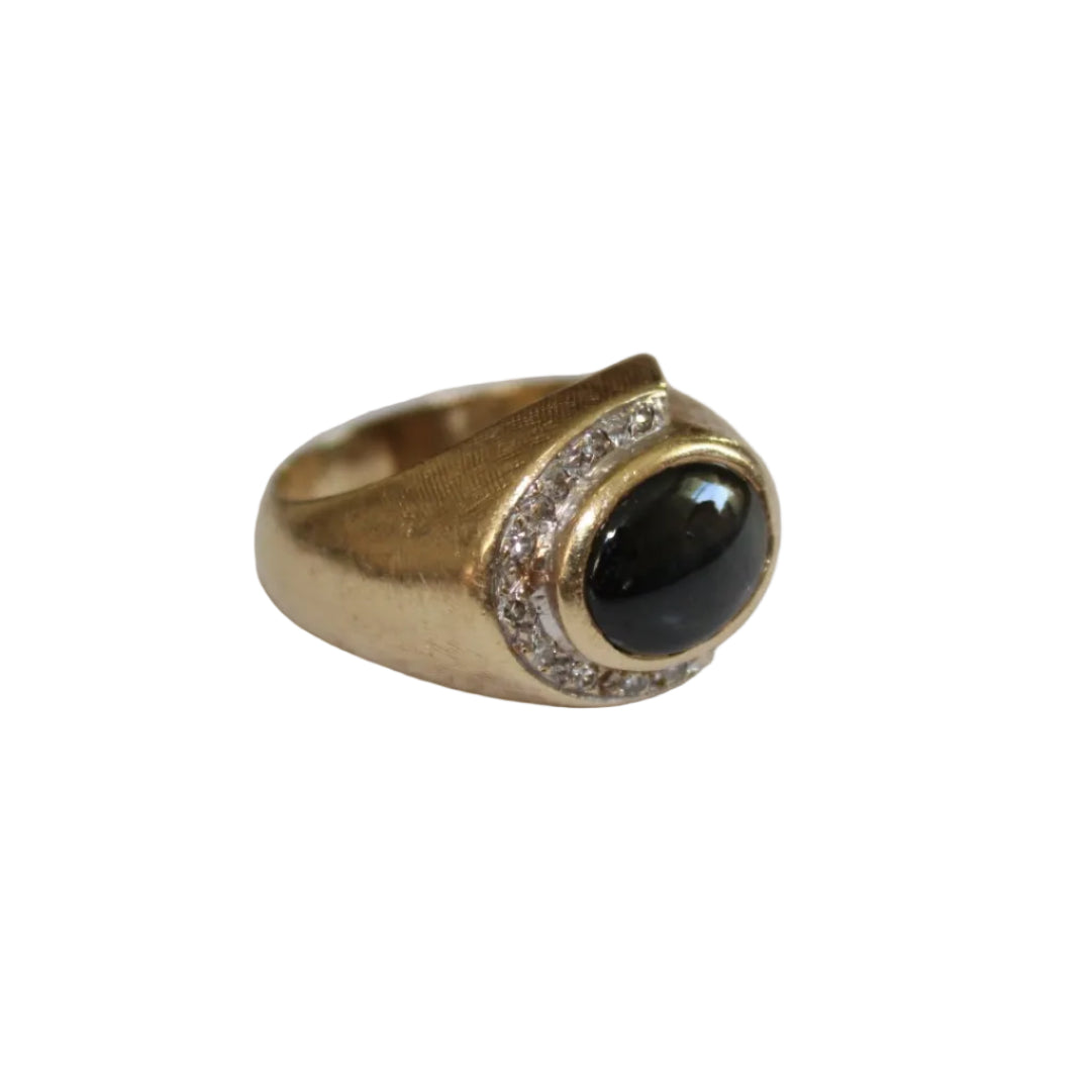 Gold ring with a black gemstone on a light gray background