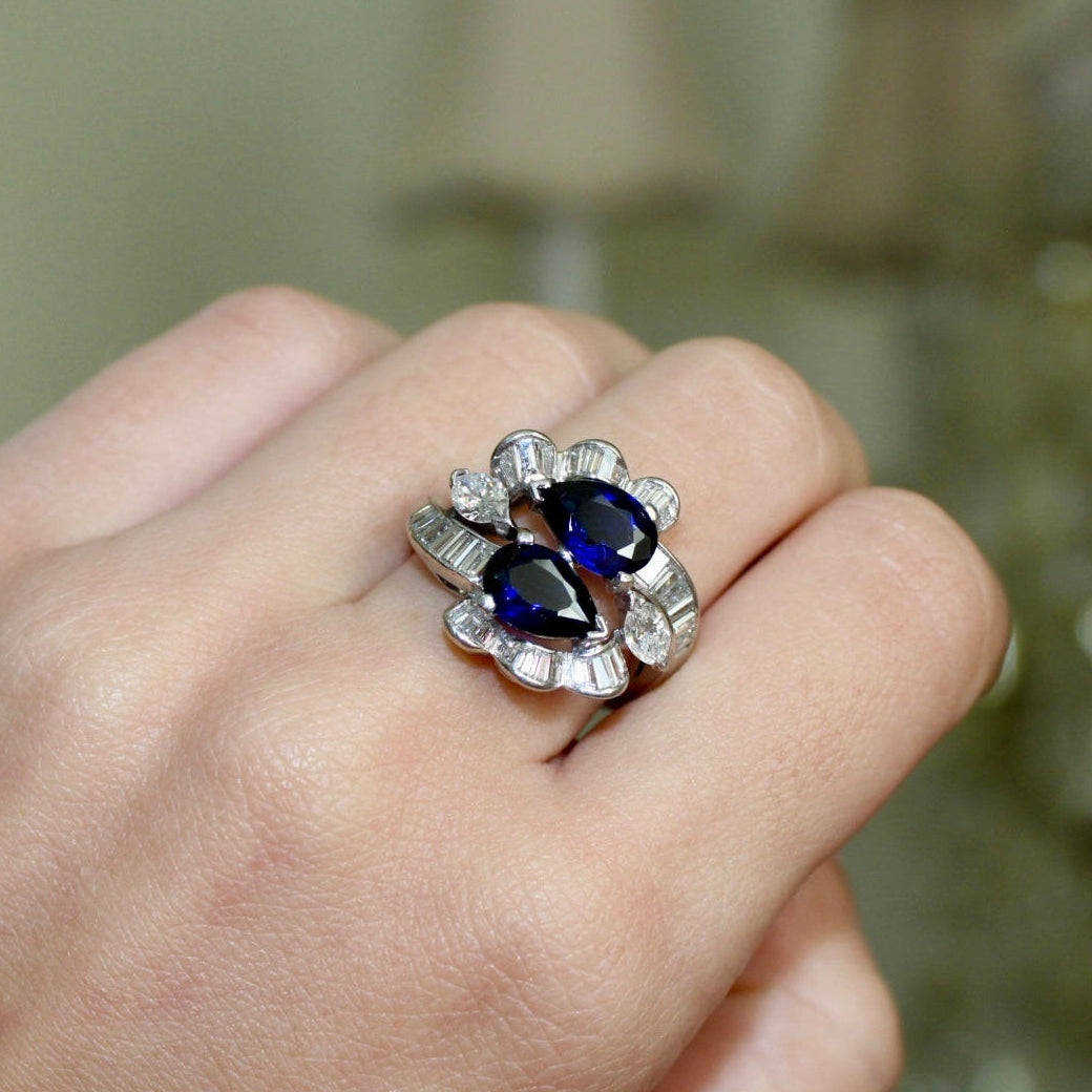 Silver ring with blue gemstones on a hand against a blurred background