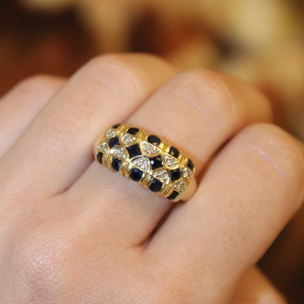 Gold and black diamond ring on a finger with a blurred background