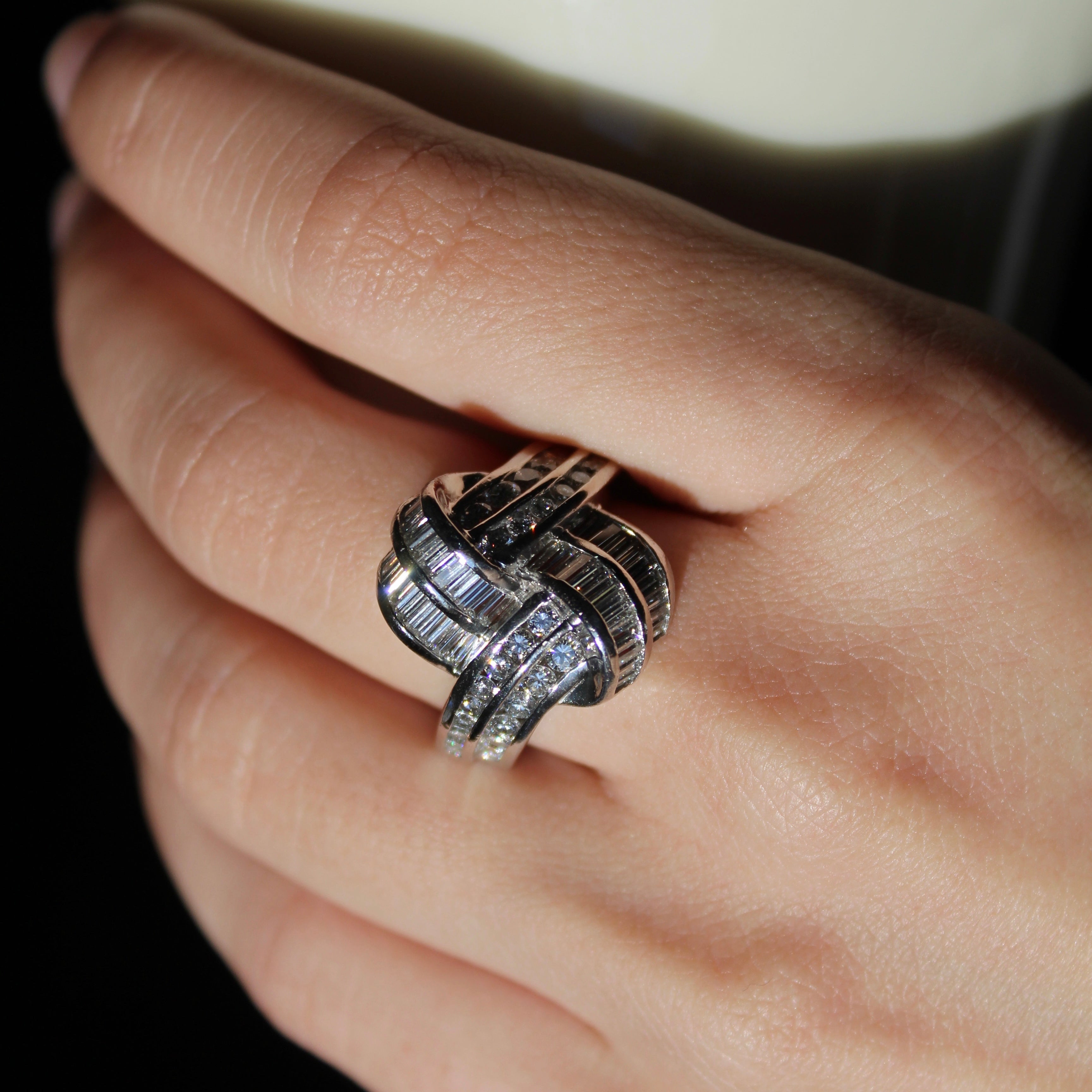 Hand wearing a silver ring with a dark background