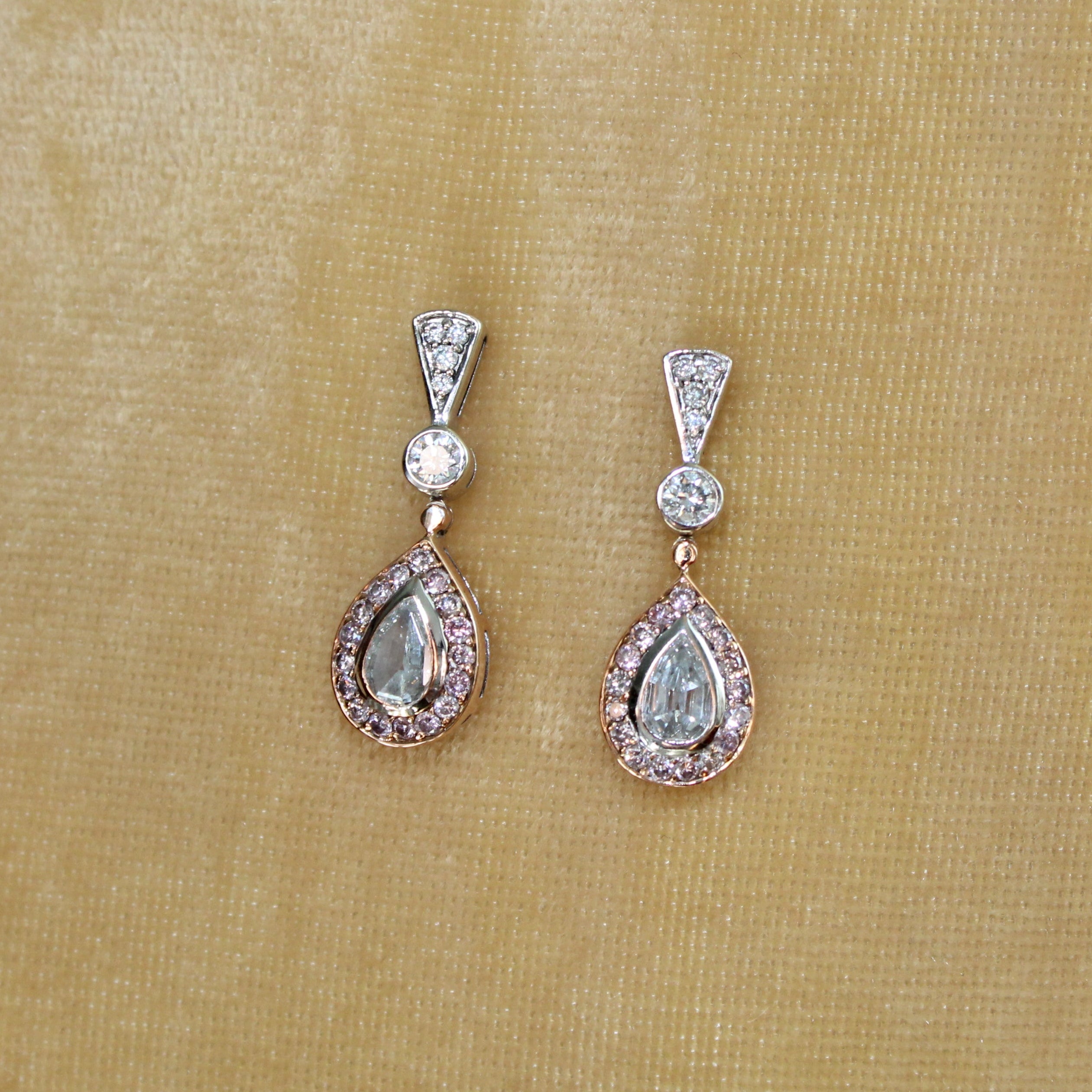 Pair of diamond earrings on a beige fabric background