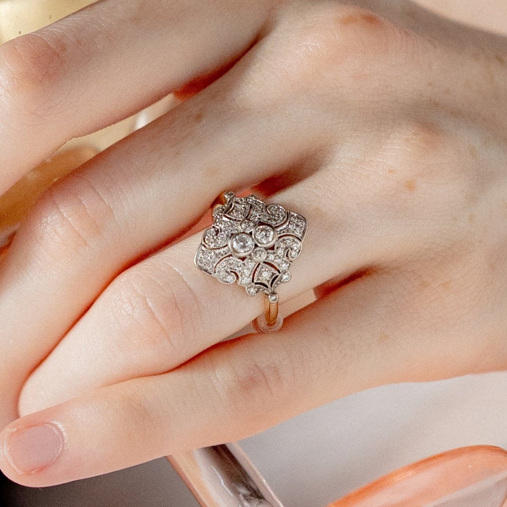 Close-up of a hand wearing a decorative ring with a blurred background